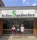 Die drei Gewinner stehen vor dem Eingang der Oberschule in den Sandwehen.